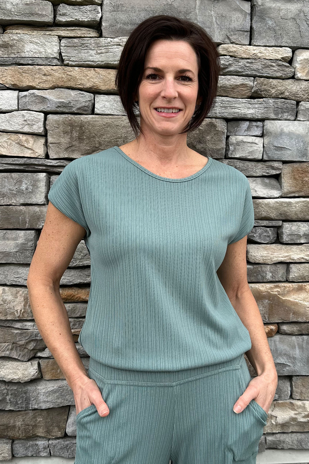 Aldila Summer 2024  This stretchy fabric top features a subtle line design pattern and a classic round neck. Its comfy fit and cap sleeves make it perfect for any casual occasion