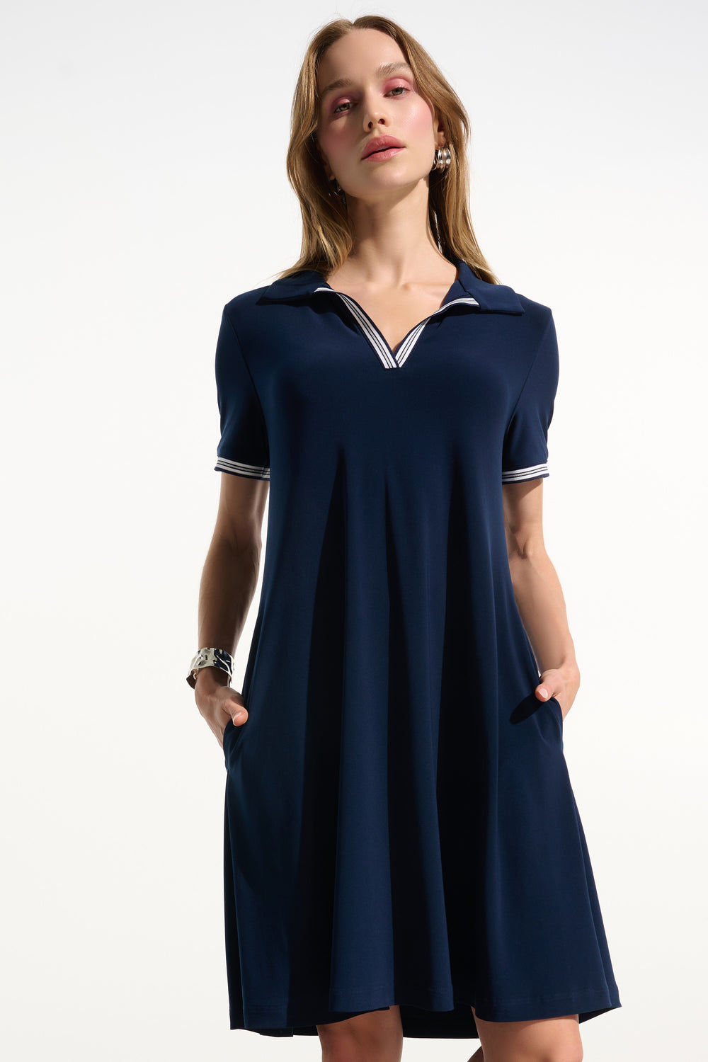 Woman wearing a navy blue dress with white trim on a white background