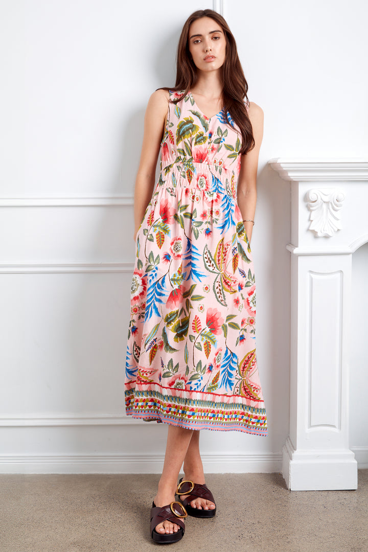 Woman wearing a colorful floral dress against a white wall.