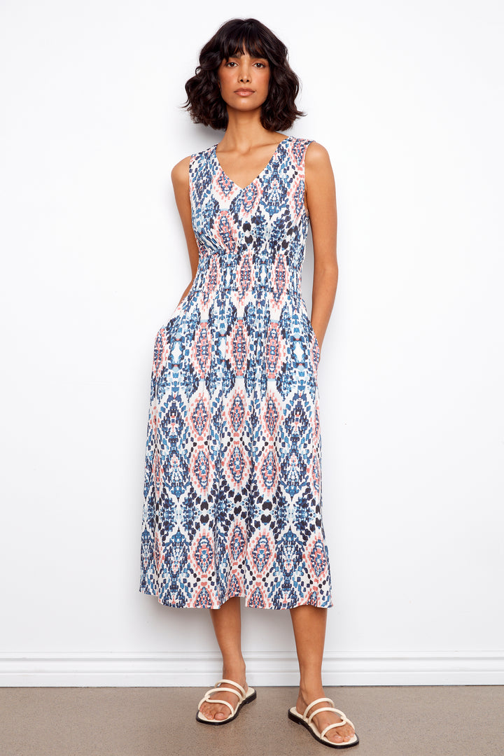 Woman wearing a sleeveless patterned dress against a white background