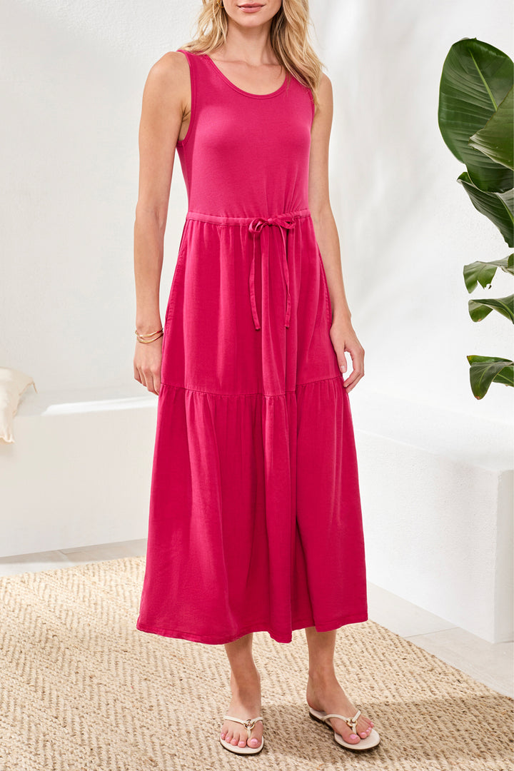 Woman wearing a pink dress standing in a room with a plant in the background