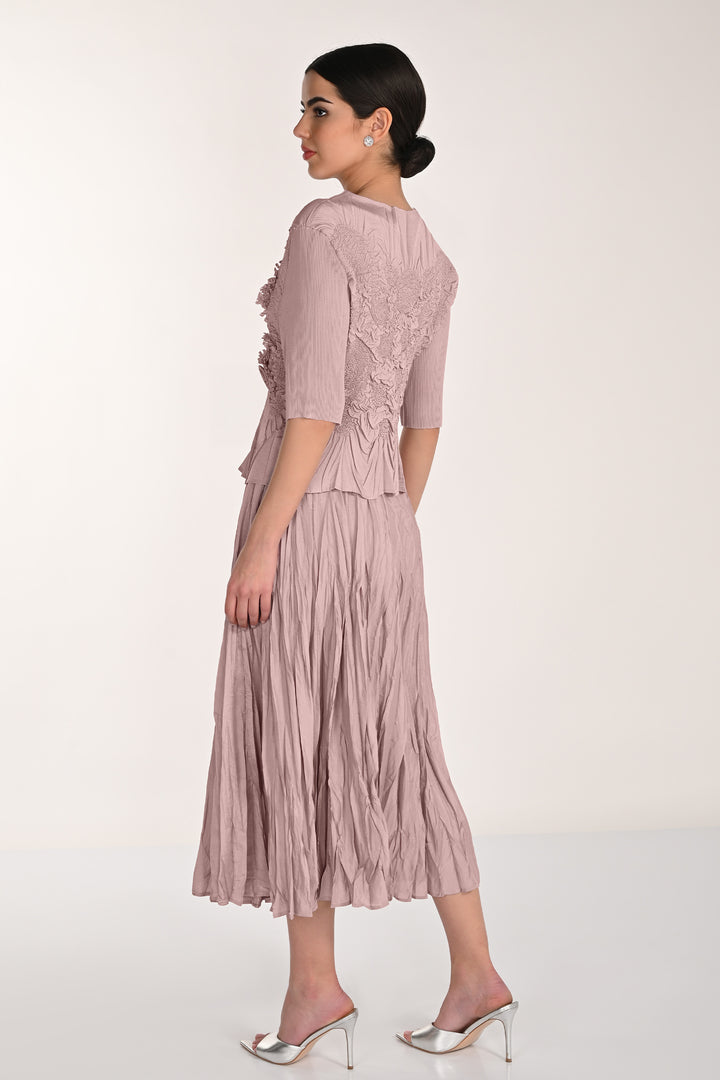 Woman wearing a pink pleated skirt with a textured top and pleated skirt on a white background