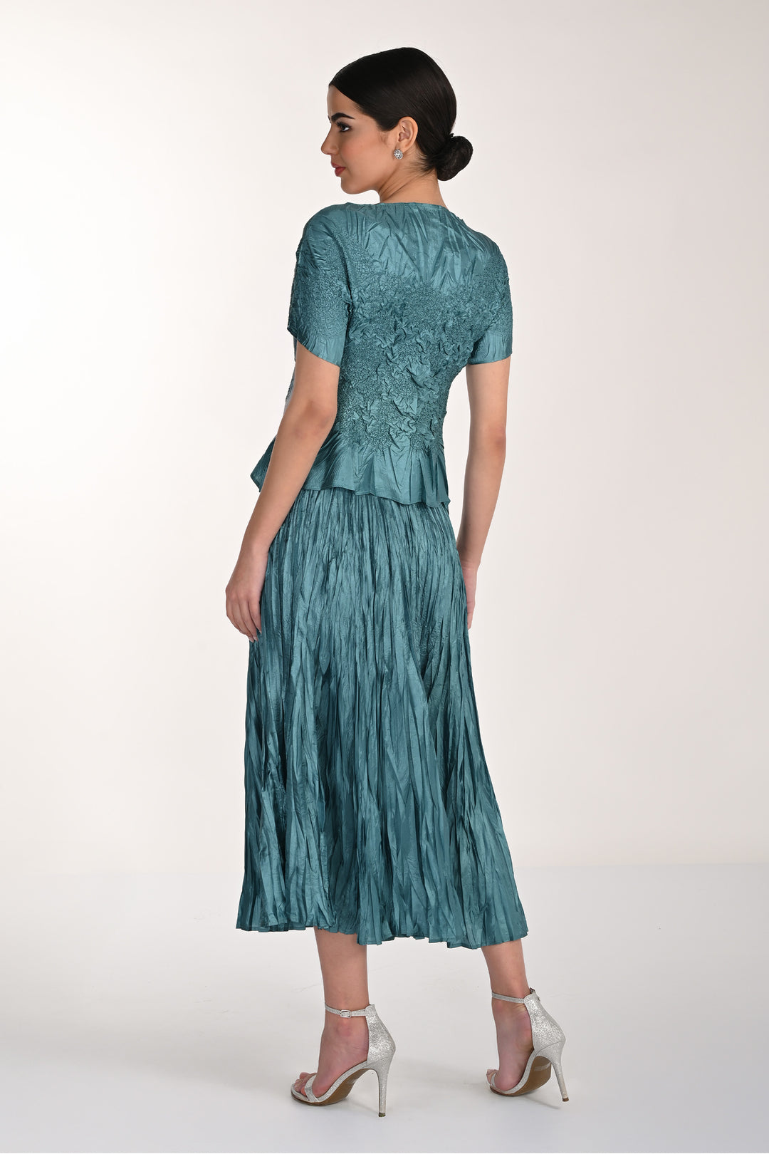 Woman wearing a teal skirt and top with a textured skirt and lace top on a white background