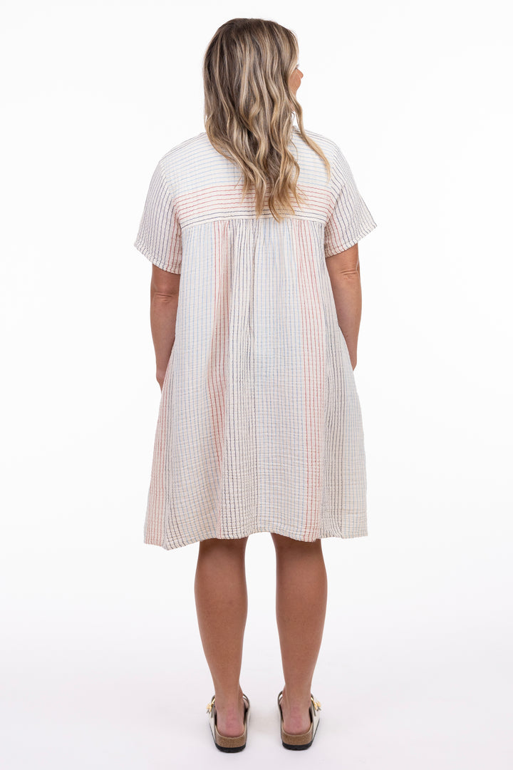 Woman wearing a white dress with red stripes from behind on a white background