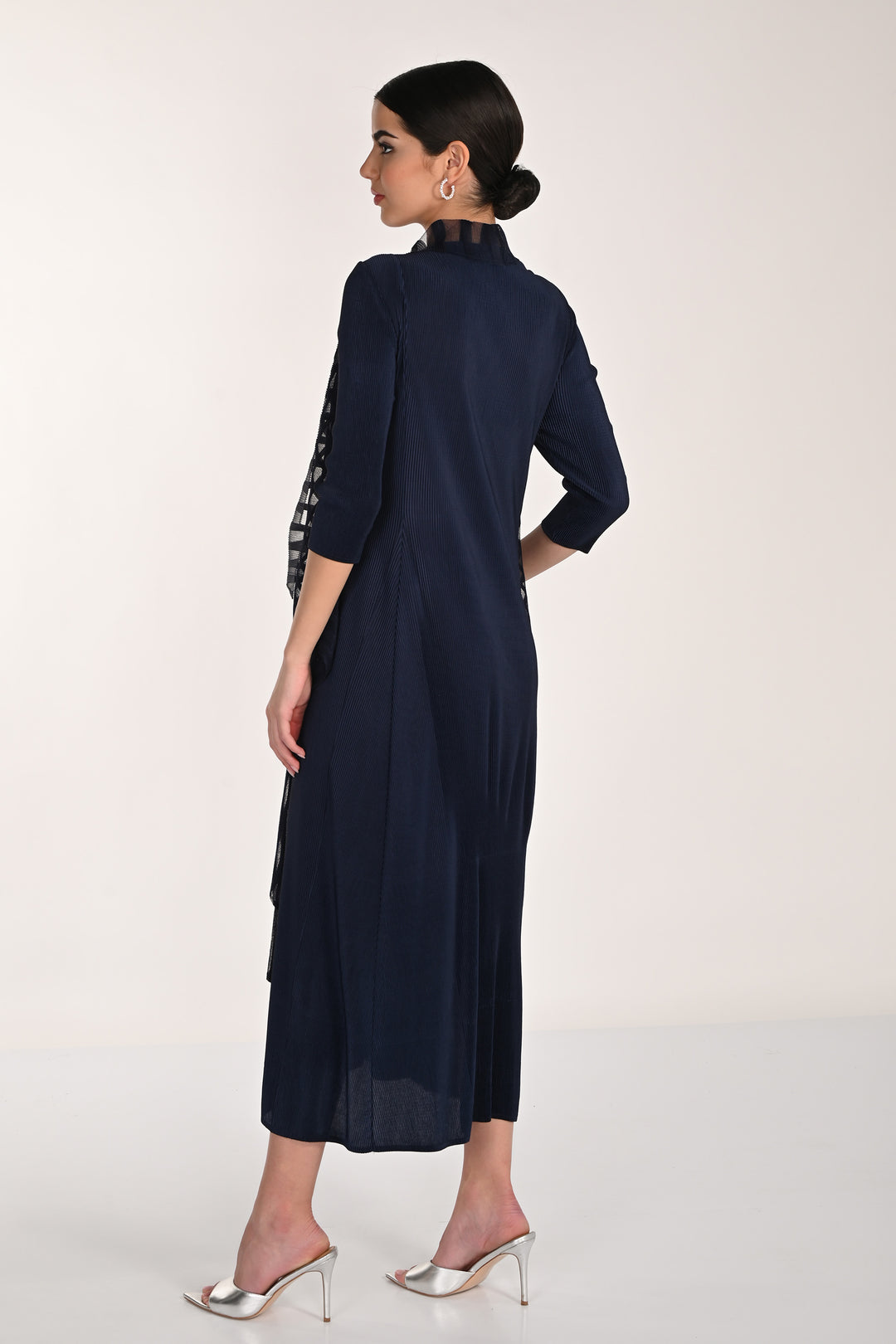 Woman wearing a navy blue dress with lace sleeves on a white background