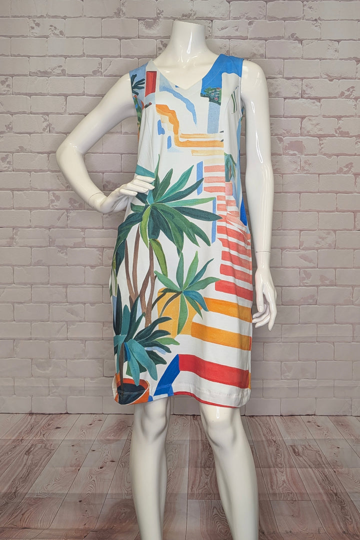 Mannequin wearing a colorful sleeveless dress with tropical patterns against a brick wall.