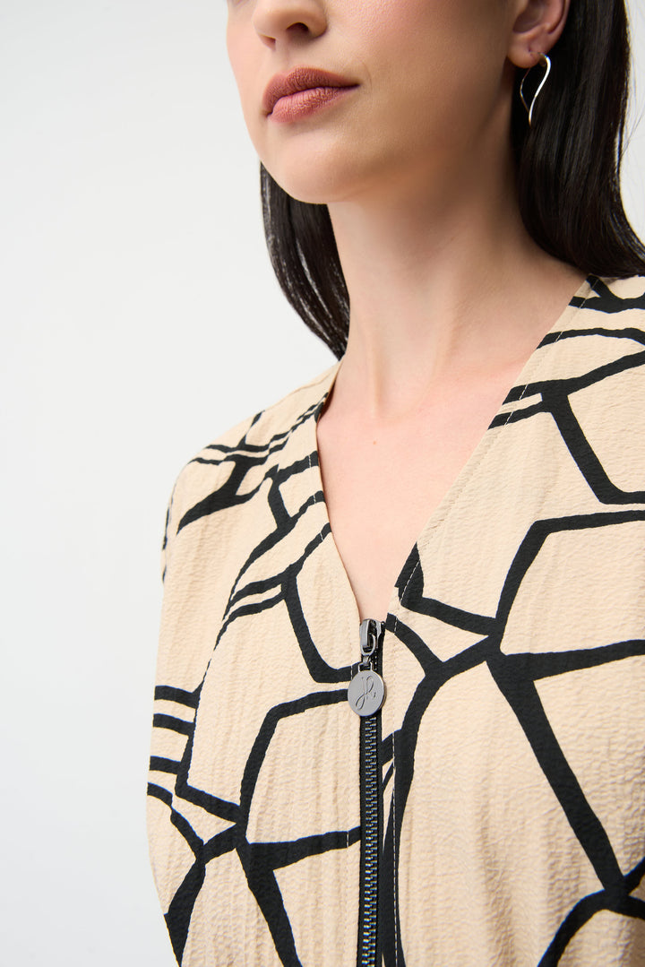 Close-up of a person wearing a beige cardigan with black geometric pattern on a light gray background