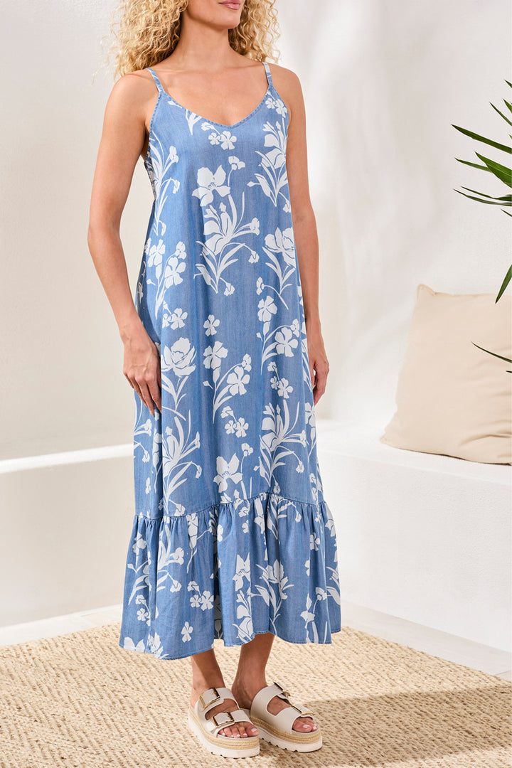 Woman wearing a blue floral long dress in a minimal indoor setting