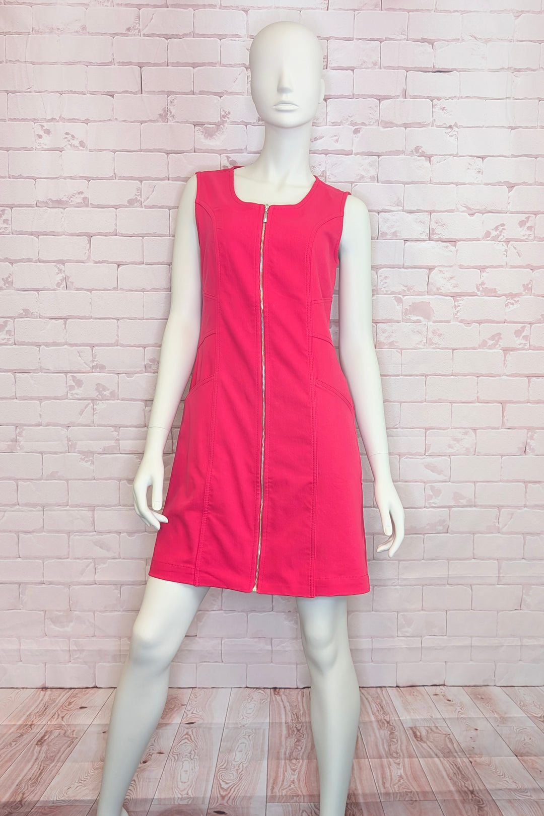 Mannequin wearing a red sleeveless dress with a zipper on a light brick wall background