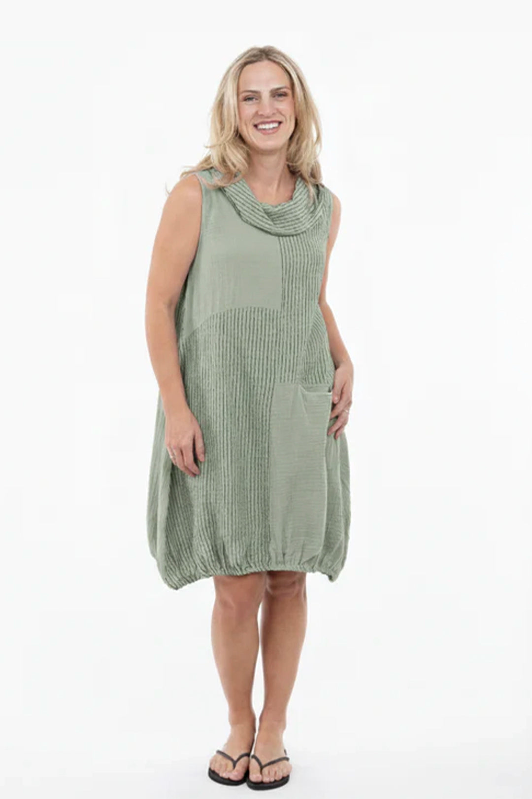 Woman wearing a green sleeveless dress with a cowl neck on a white background
