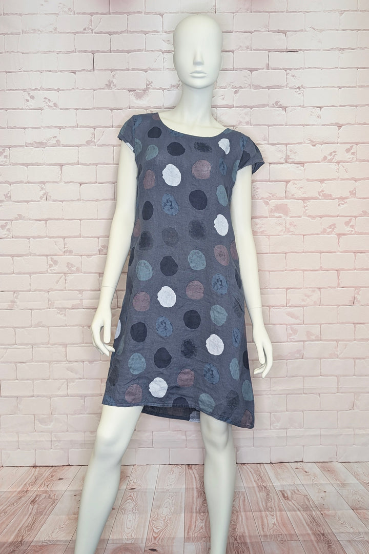 Mannequin wearing a polka dot linen dress against a brick wall.