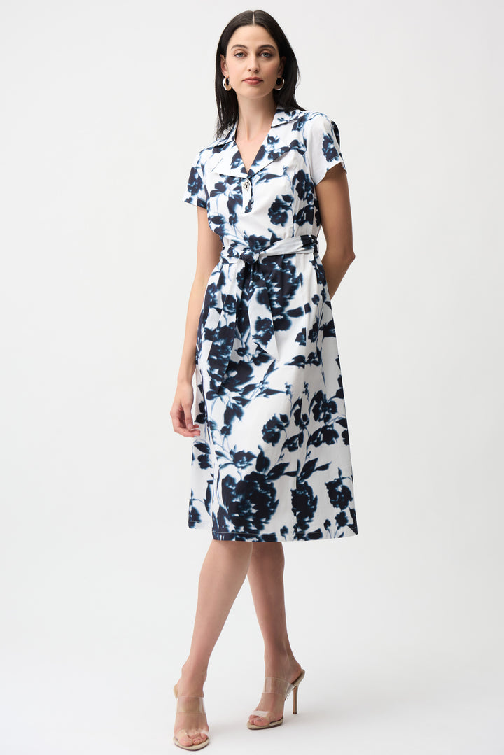 Woman wearing a white dress with blue floral pattern and sash belt on a white background