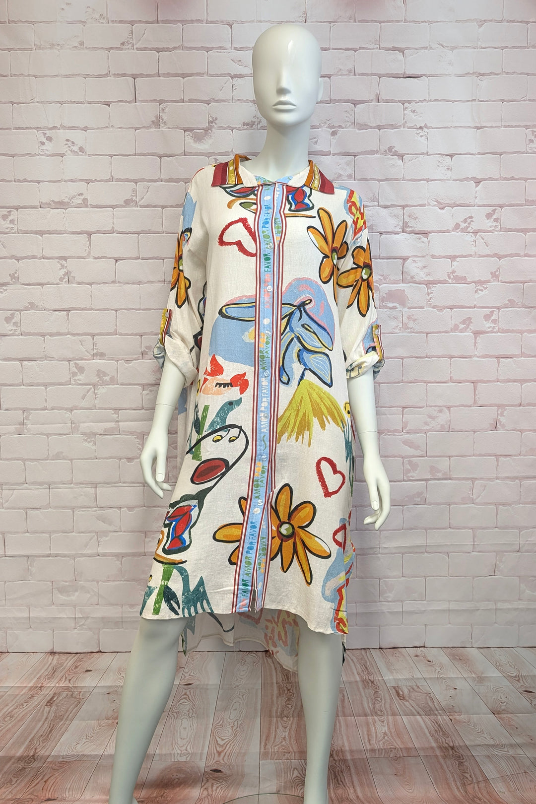 Mannequin wearing a colorful floral shirt dress with a white brick wall background