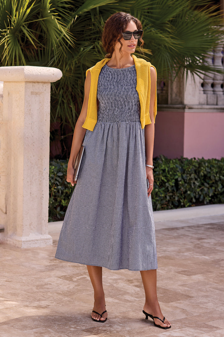 Woman in a gray sleeveless bodice dress with a yellow cardigan standing outdoors.