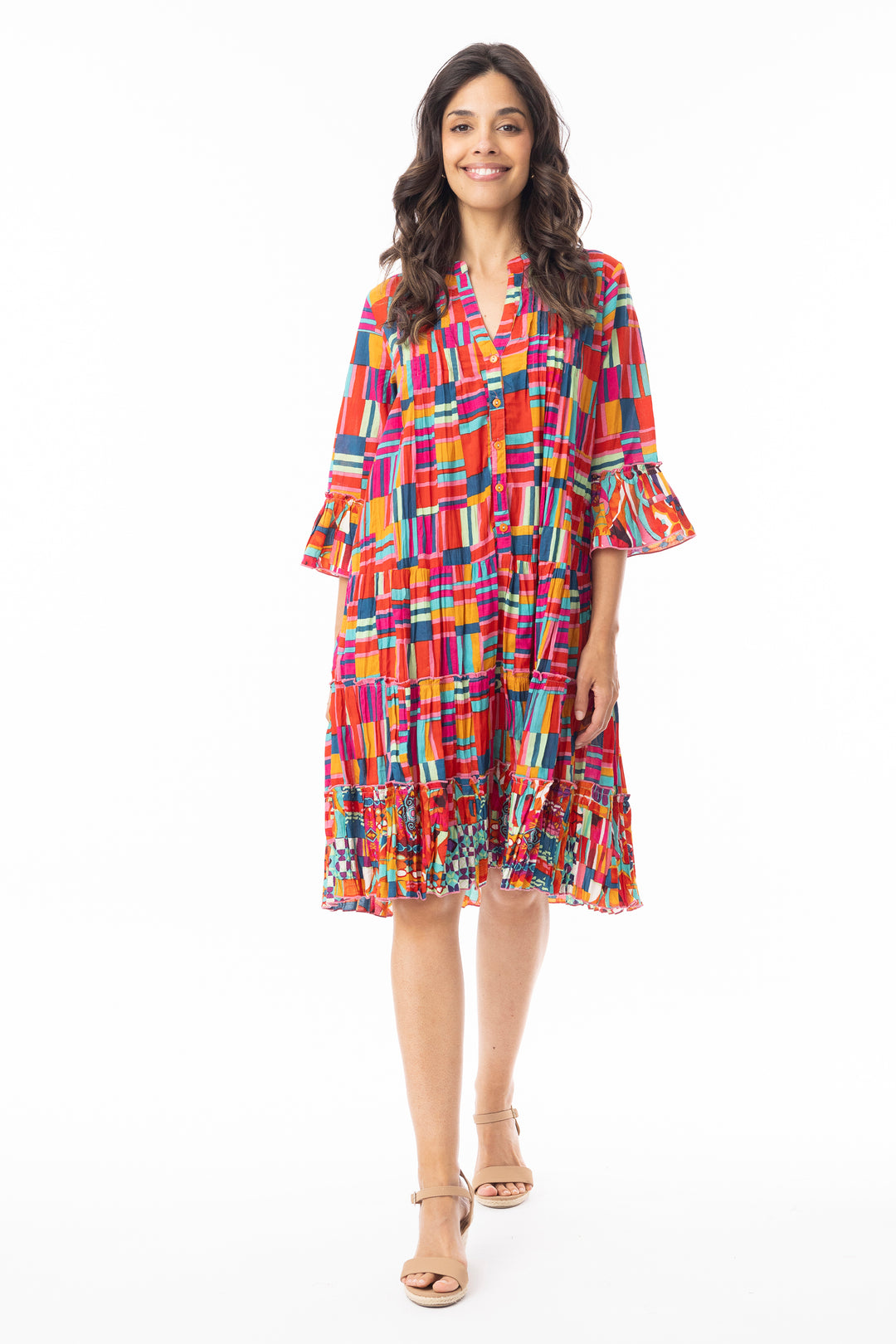 Woman wearing a colorful frill tiered patterned dress on a white background