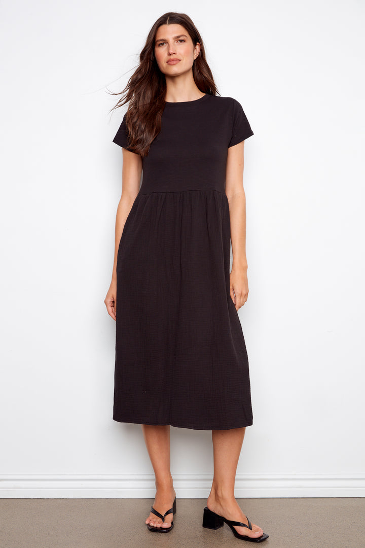 Woman wearing a black short sleeve long dress against a white background
