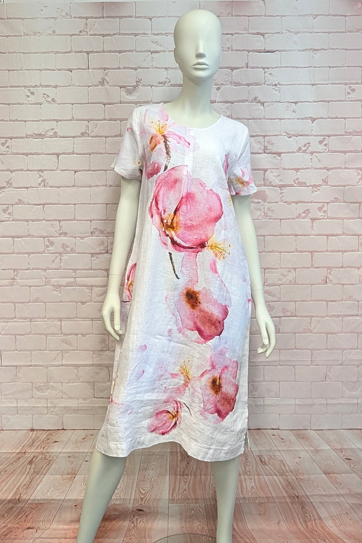 Mannequin wearing a floral linen dress against a light brick wall.