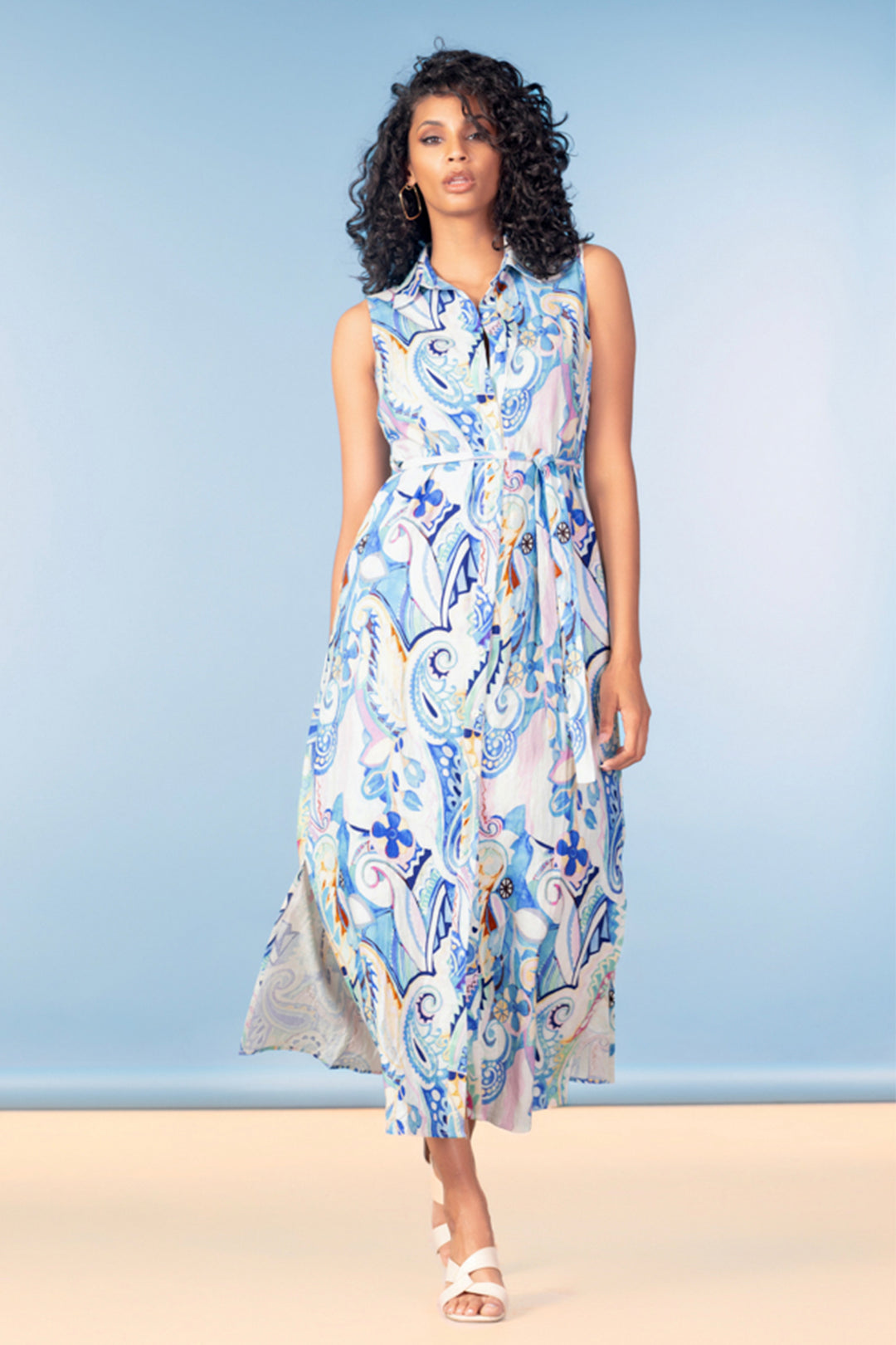 Woman wearing a sleeveless, patterned summer dress against a light blue background