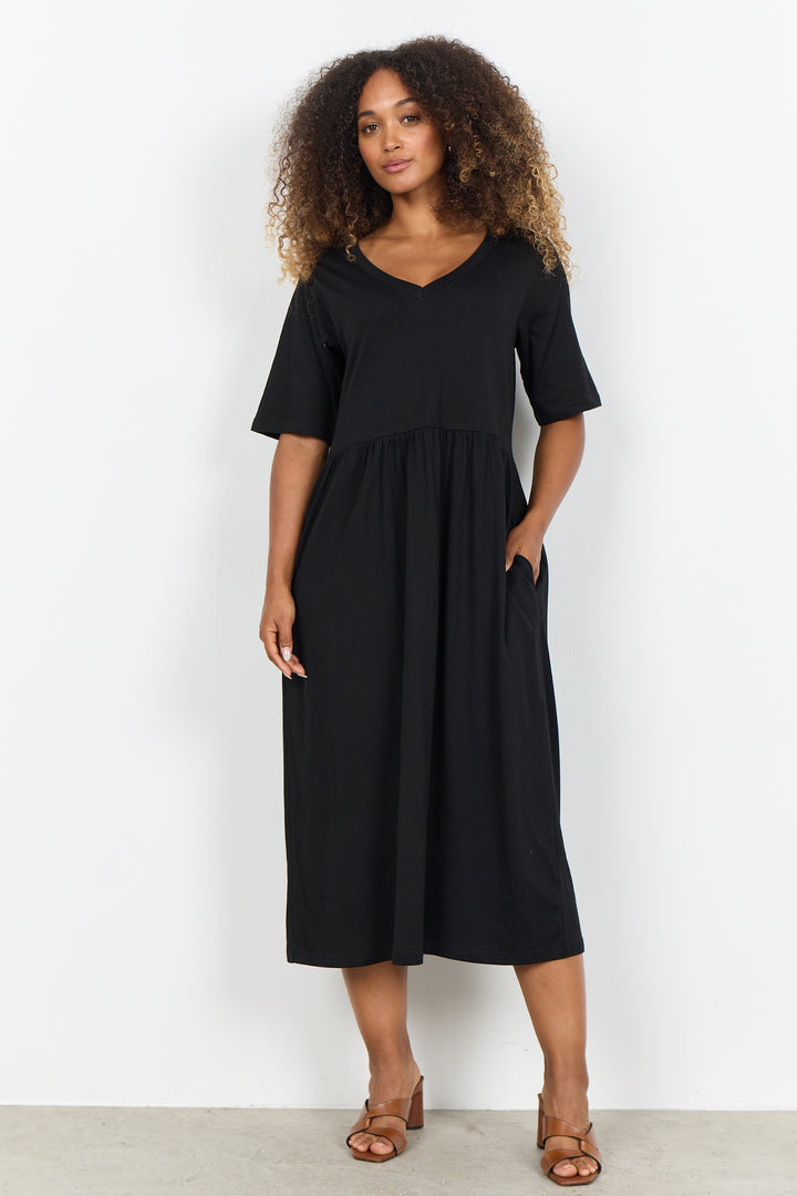 Woman wearing a midi length t-shirt dress on a white background. 