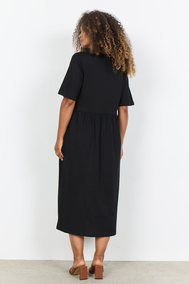 Woman wearing a midi length t-shirt dress on a white background. 