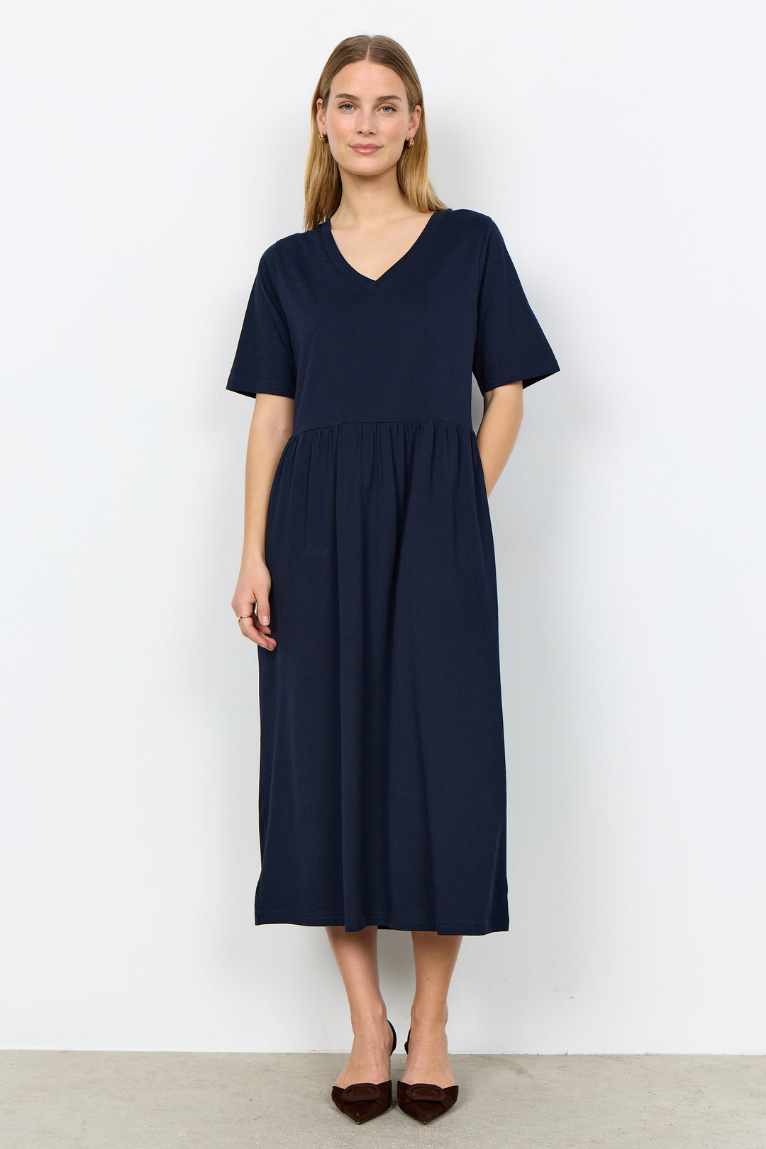 Woman wearing a midi length t-shirt dress on a white background. 
