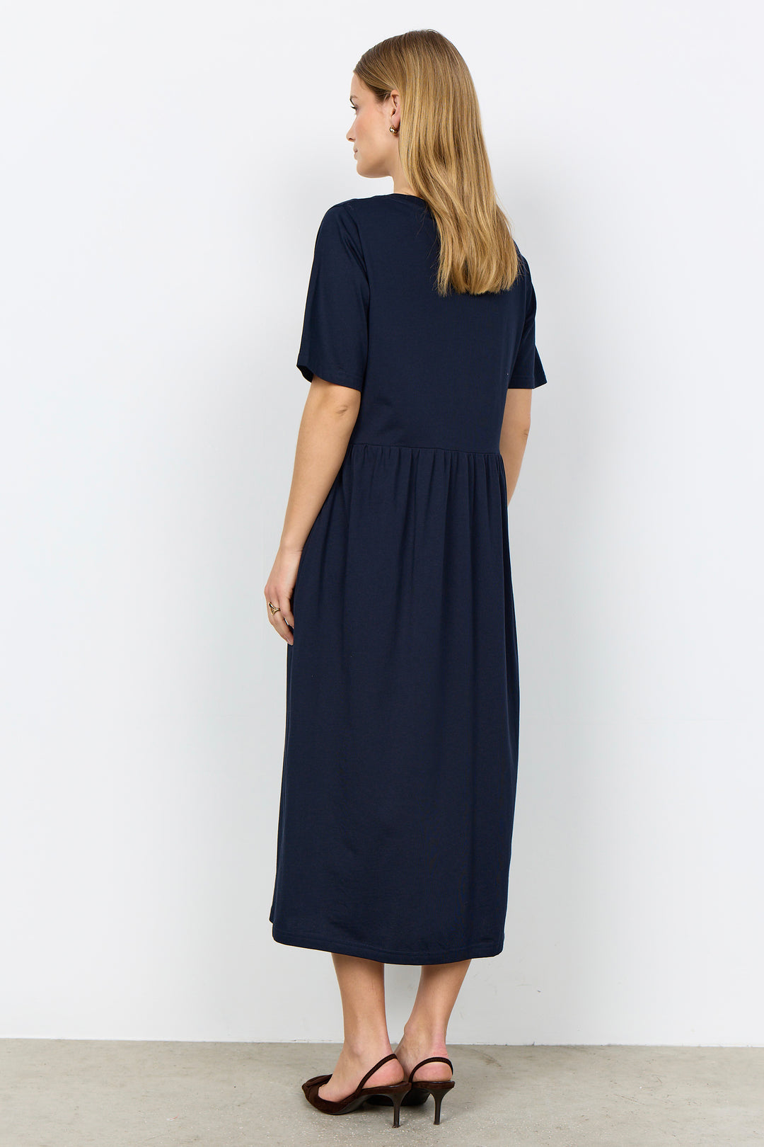 Woman wearing a midi length t-shirt dress on a white background. 