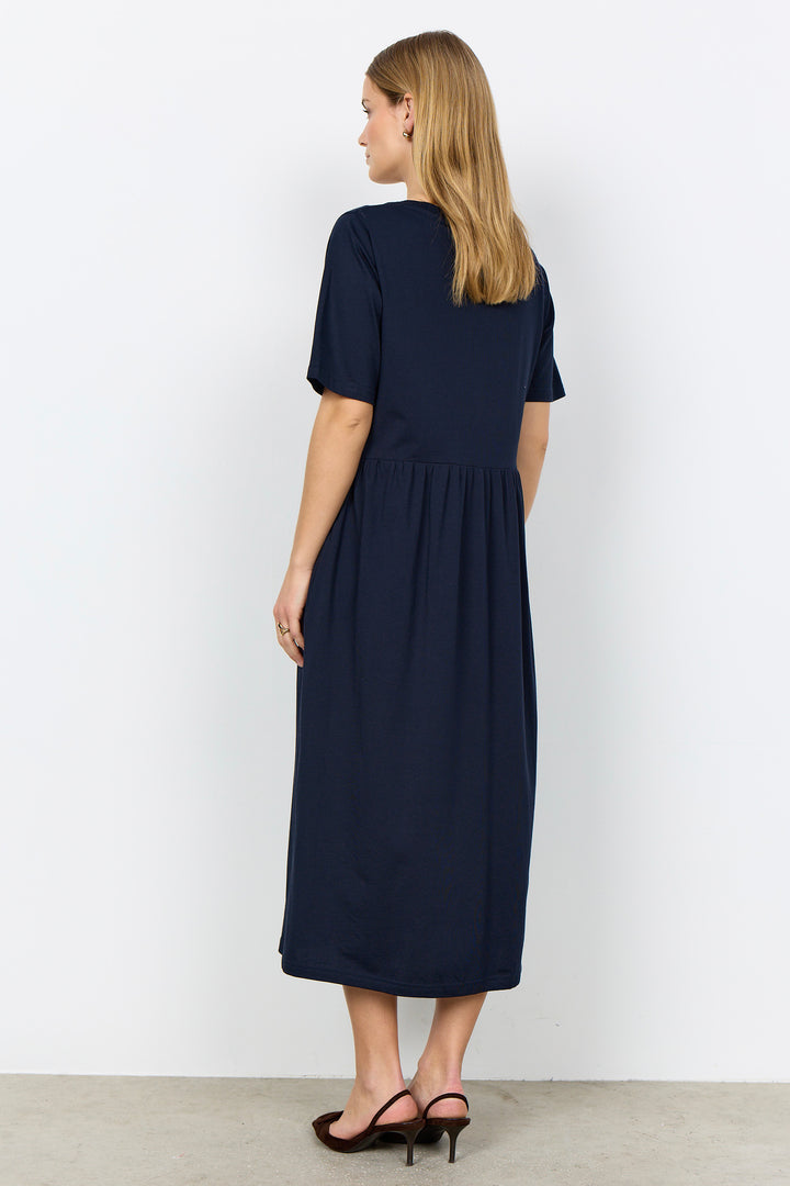 Woman wearing a midi length t-shirt dress on a white background. 