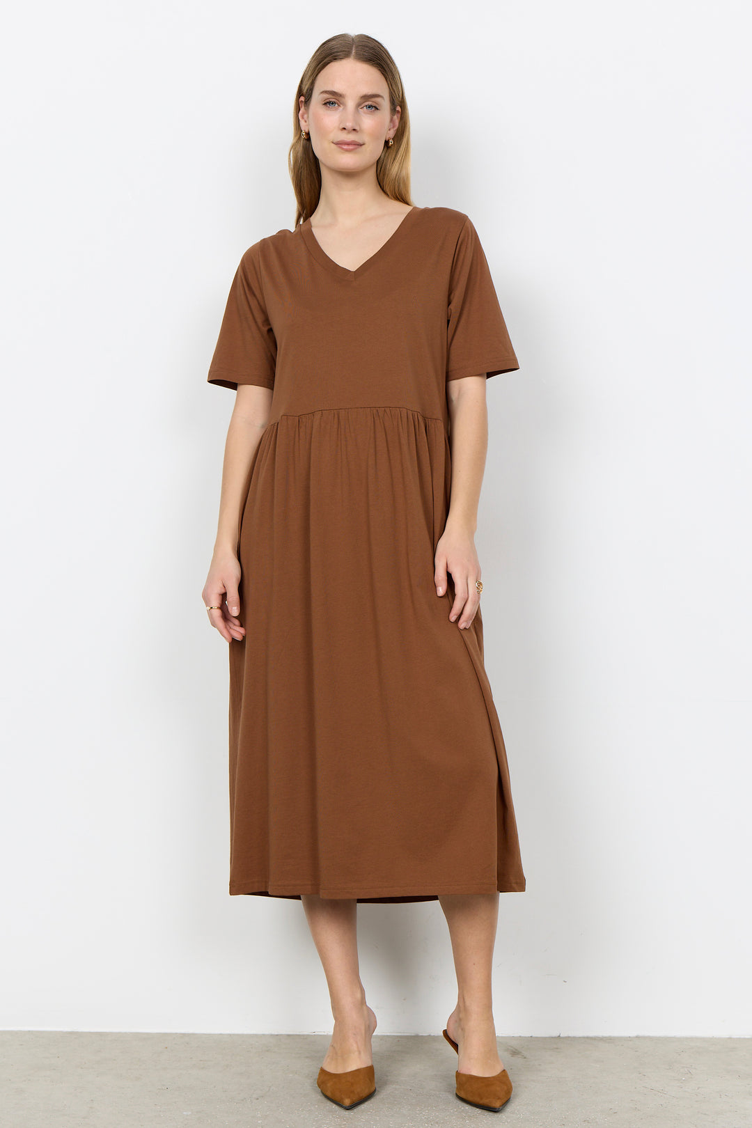 Woman wearing a midi length t-shirt dress on a white background. 