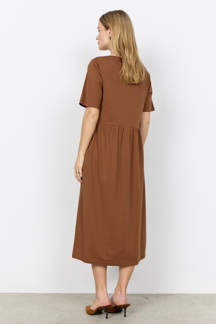 Woman wearing a midi length t-shirt dress on a white background. 