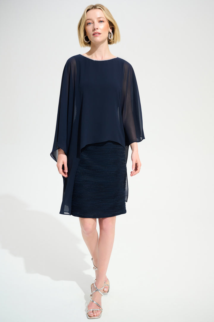 Woman wearing a navy dress with sheer sleeves on a white background
