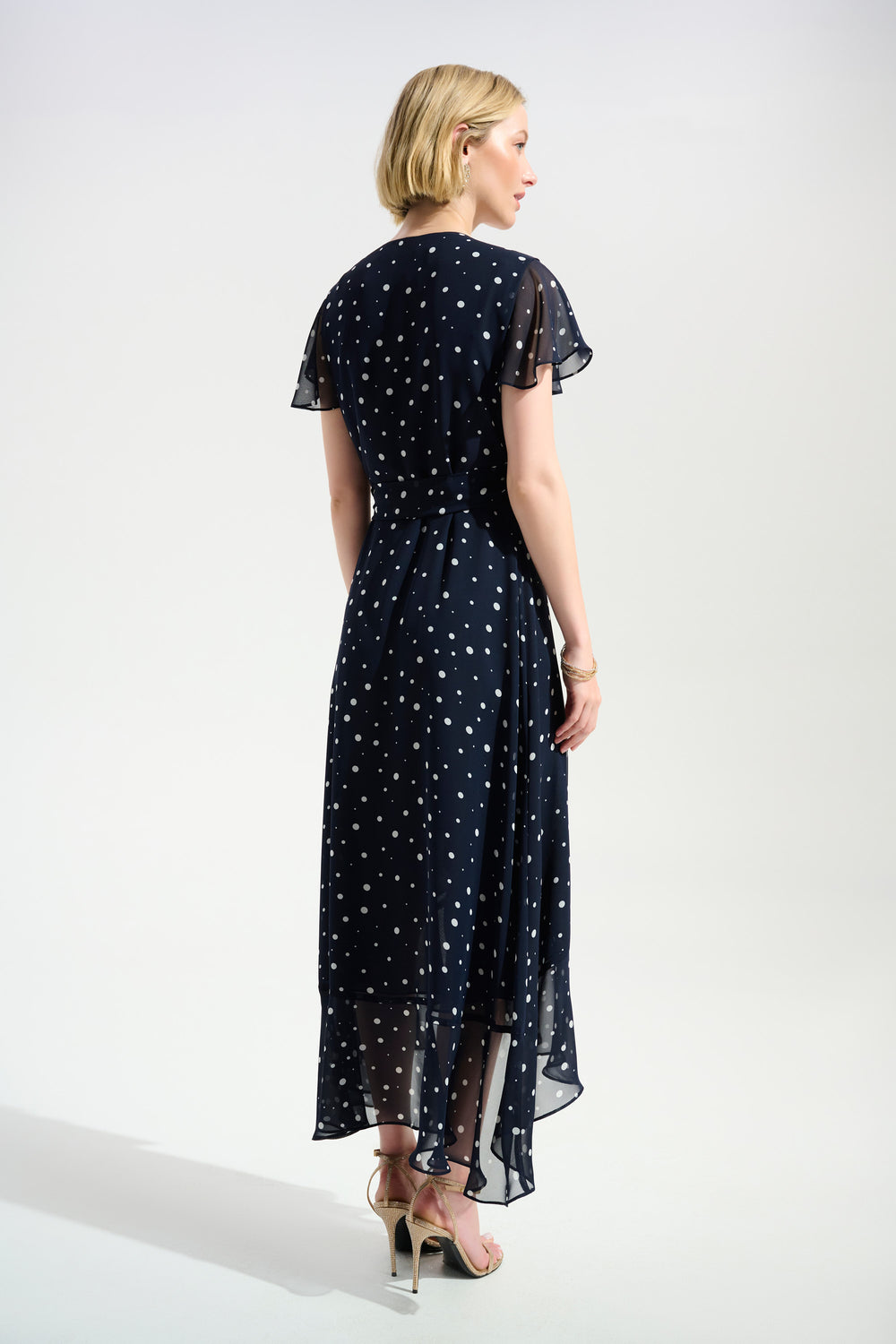 Woman wearing a navy blue dress with white polka dots on a white background