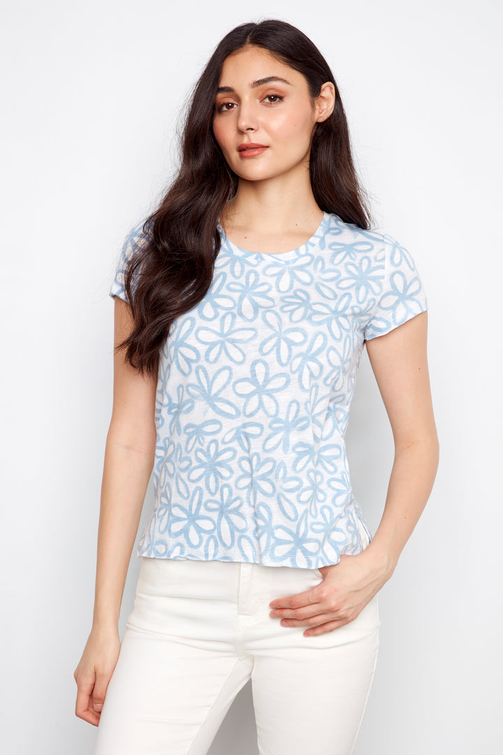Woman wearing a light blue floral patterned shirt against a white background