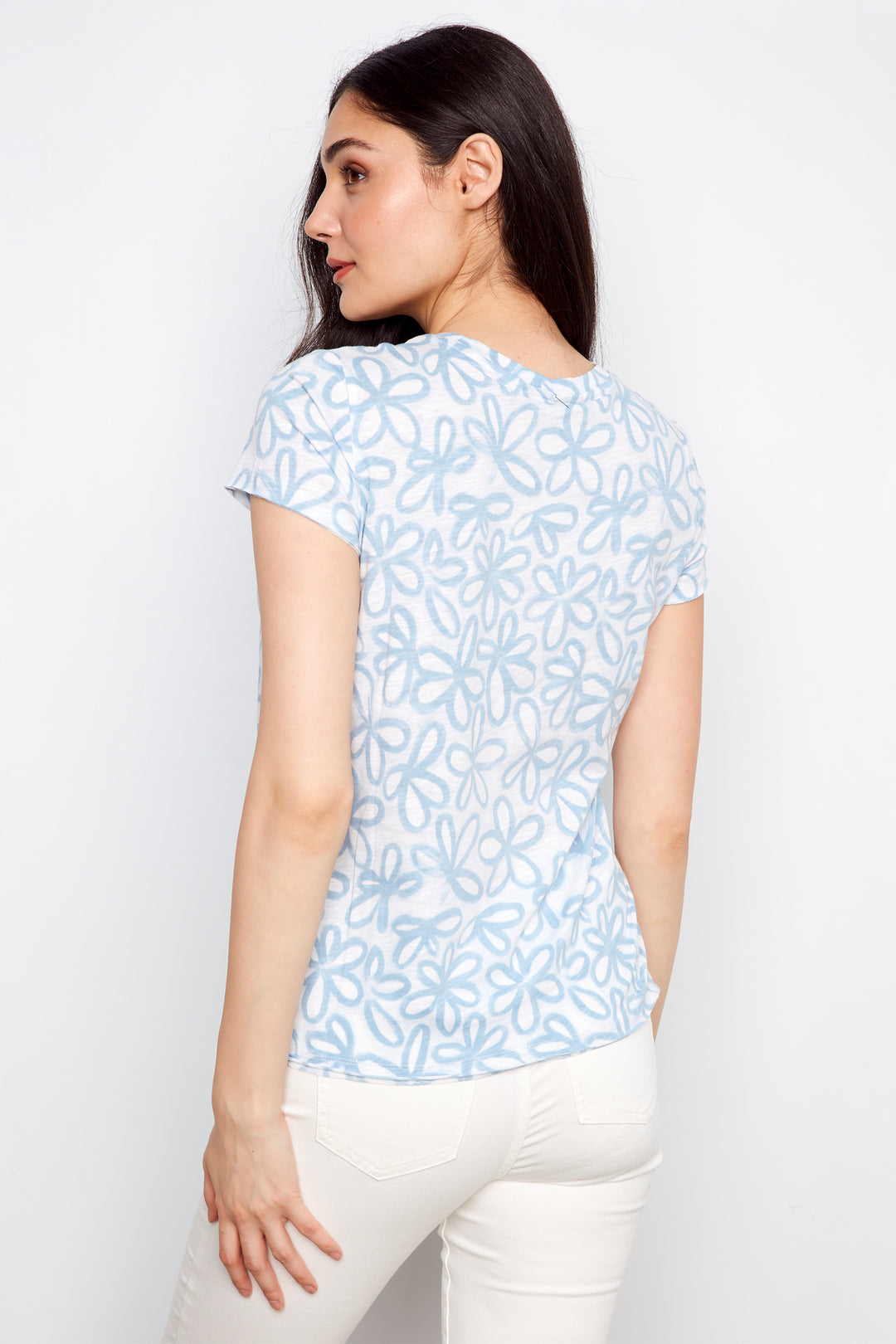 Woman wearing a light blue floral patterned top against a white background