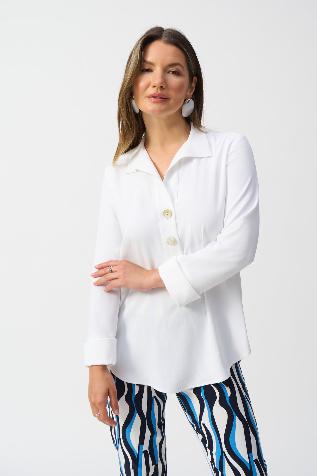 Joseph Ribkoff Spring 2025 This top features a stylish v-neck with a classic collar, giving it a more relaxed fit that is both comfortable and flattering. The soft, stretchy fabric and 3/4 length sleeves with rolled cuffs add a touch of comfort and style to this must-have piece.