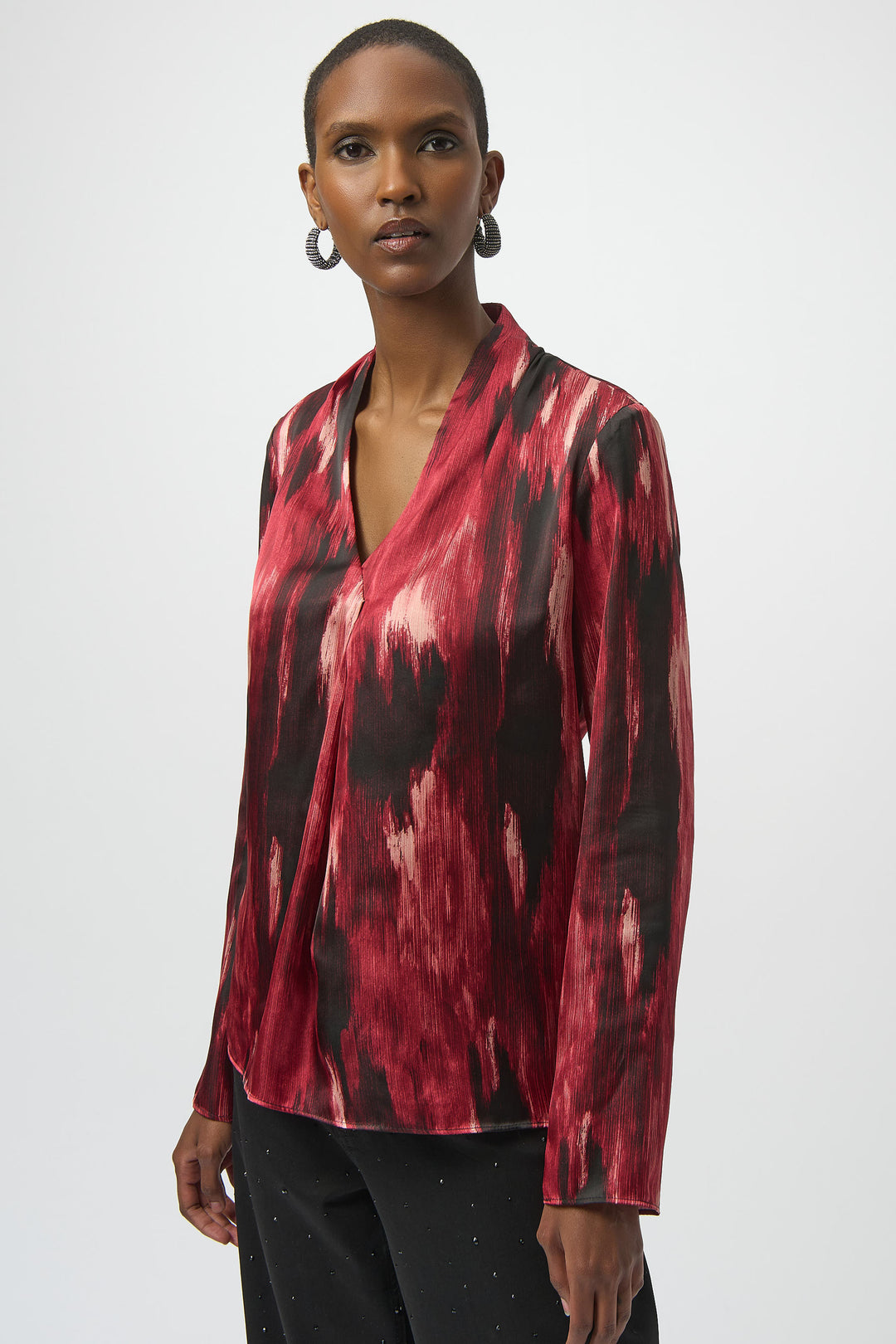 Joseph Ribkoff Fall 2025 
Elevate your wardrobe with this Black Red Oil Paint Ikat top featuring a unique wrap design and a flattering V-neckline. The long, straight sleeves add elegant coverage, while the mesmerizing colours blend seamlessly, creating a striking artistic effect. 