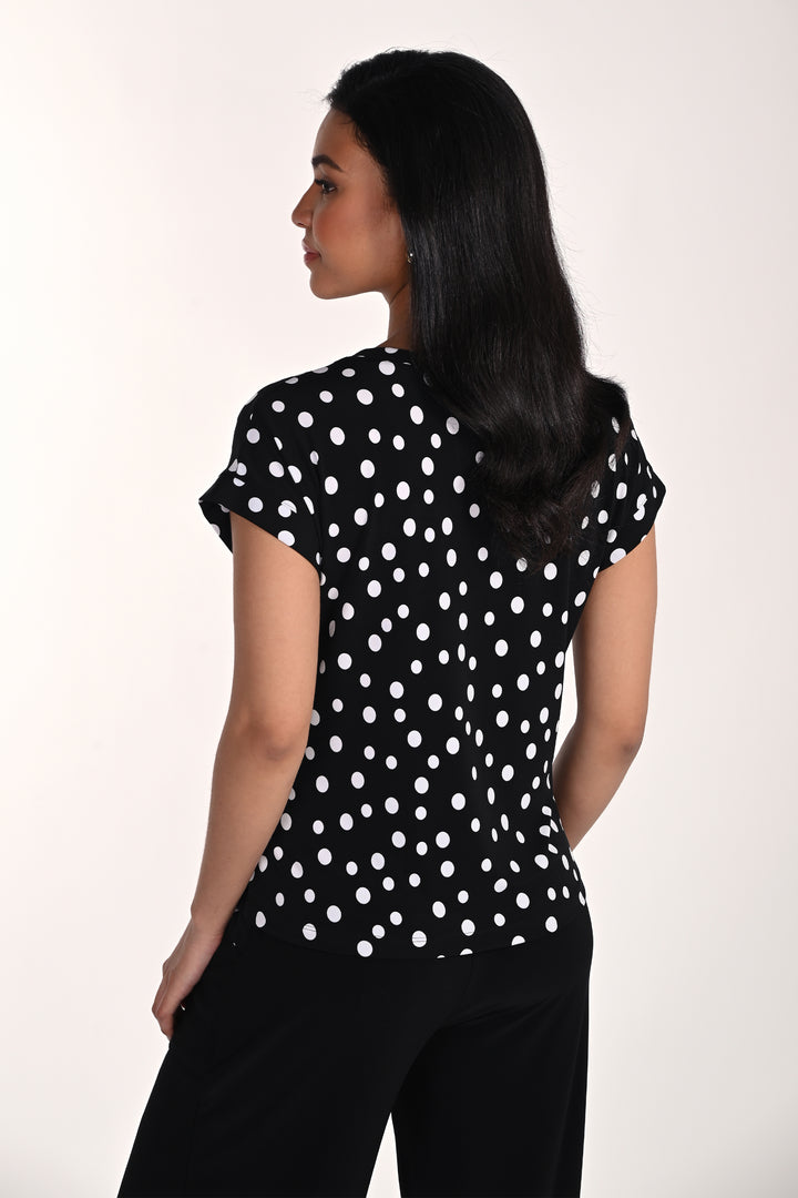 Woman wearing a black polka dot top against a white background