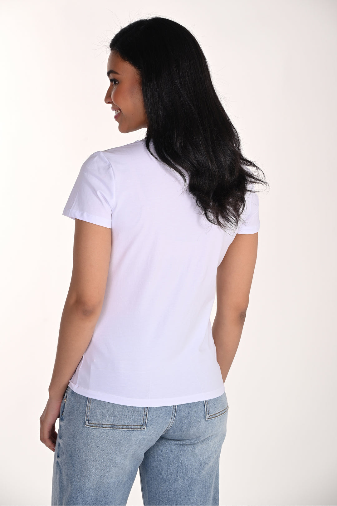 Woman wearing a plain white t-shirt and light blue jeans on a white background