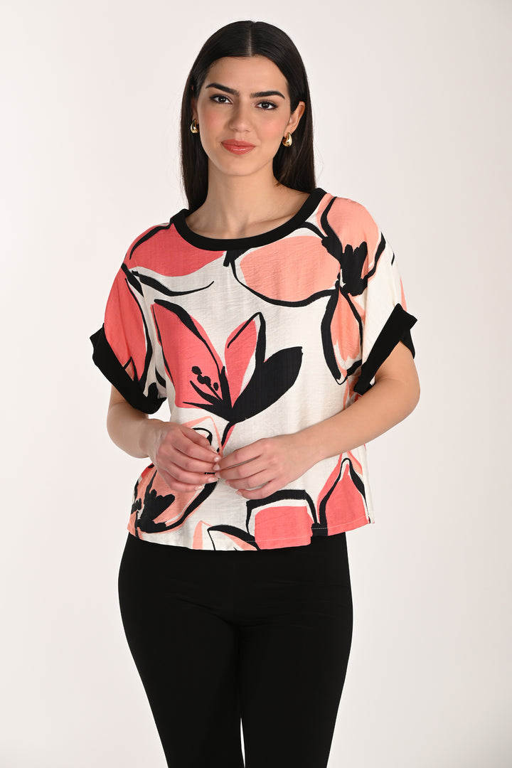 Woman wearing a colorful floral-patterned top against a white background
