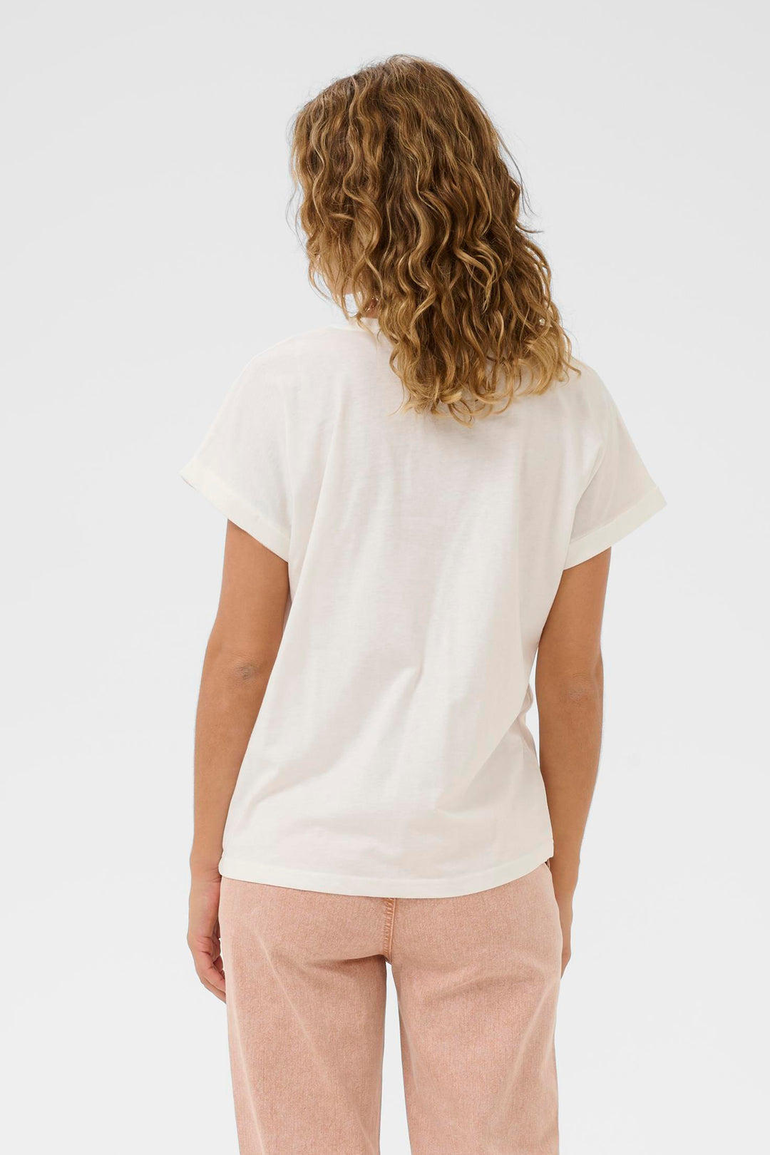 Person wearing a white t-shirt and light pink pants on a plain background
