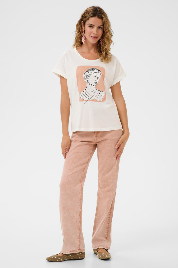 Woman wearing a white t-shirt with a graphic design and beige pants on a white background