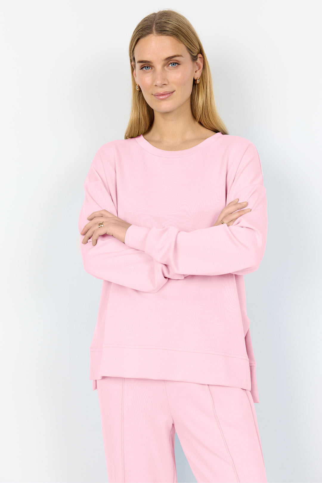 Woman wearing a pink sweater top against a white background