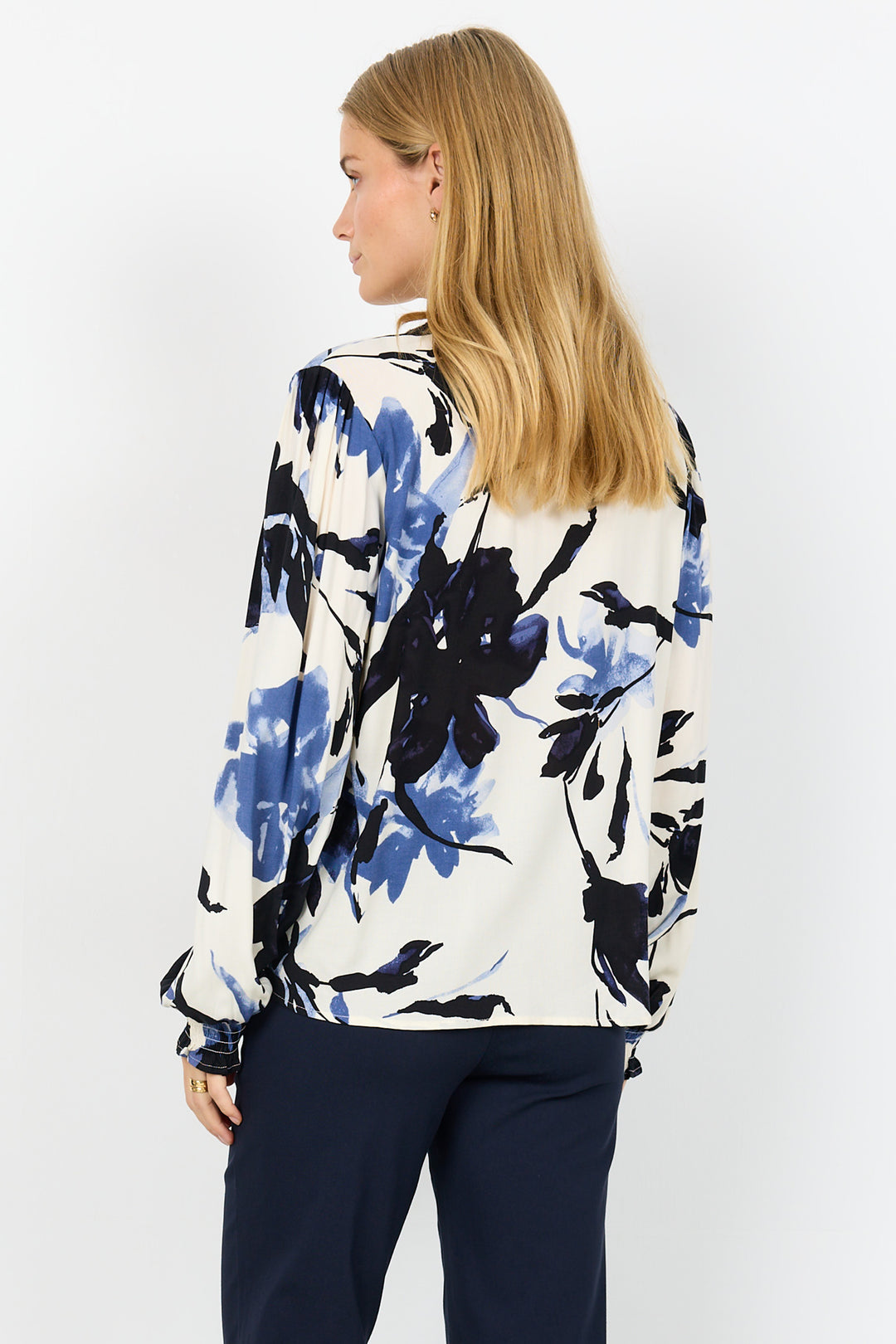 Woman wearing a floral blouse with blue and black patterns on a white background