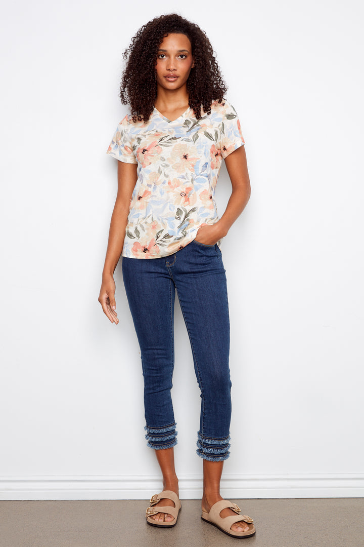 Woman wearing a floral top and blue jeans against a white background