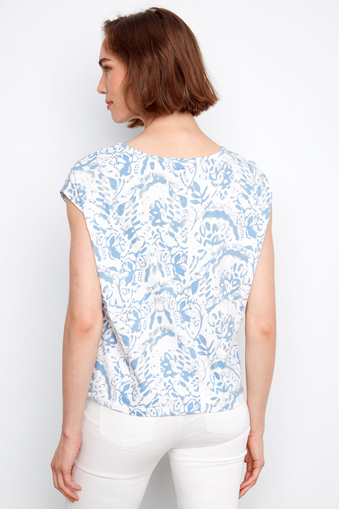 Woman wearing a white t-shirt with blue floral pattern against a white background