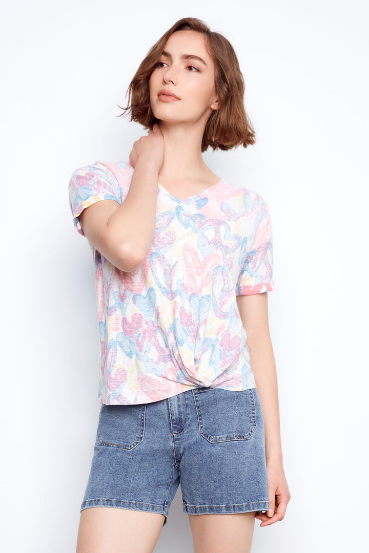 Woman wearing a colorful floral top and denim shorts on a white background