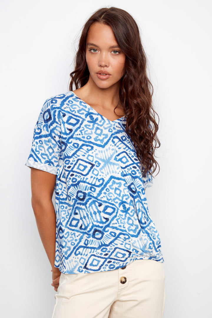 Woman wearing a blue patterned top against a white background