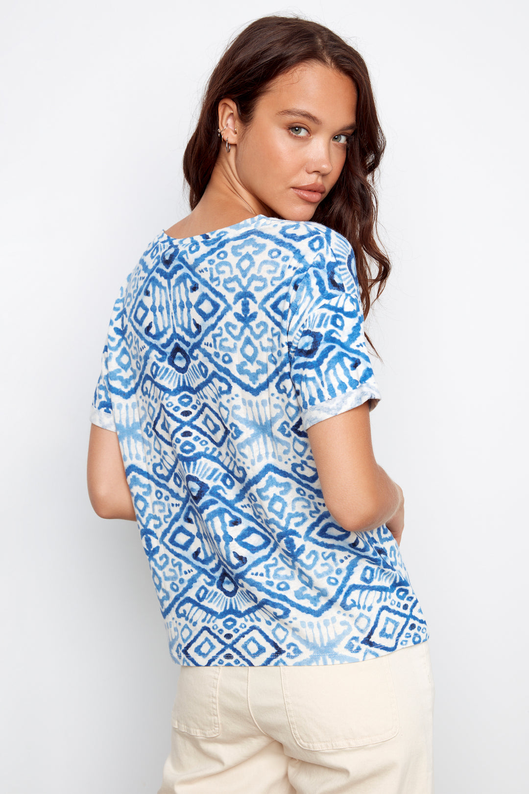 Woman wearing a blue and white patterned shirt against a plain background