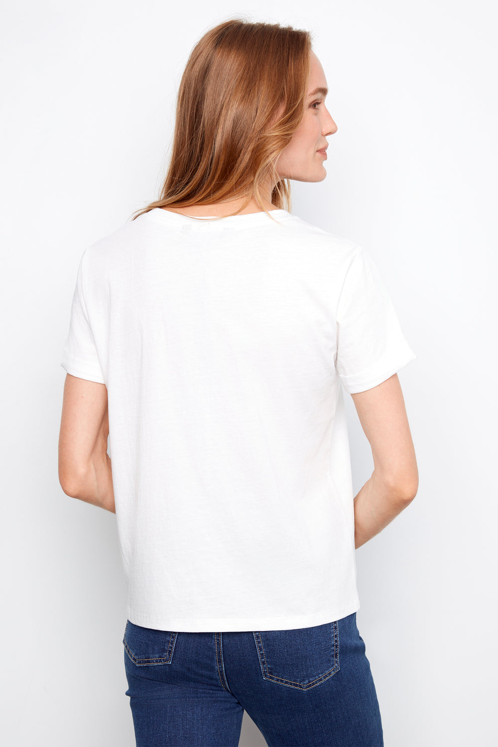 Woman wearing a white t-shirt and blue jeans on a plain background