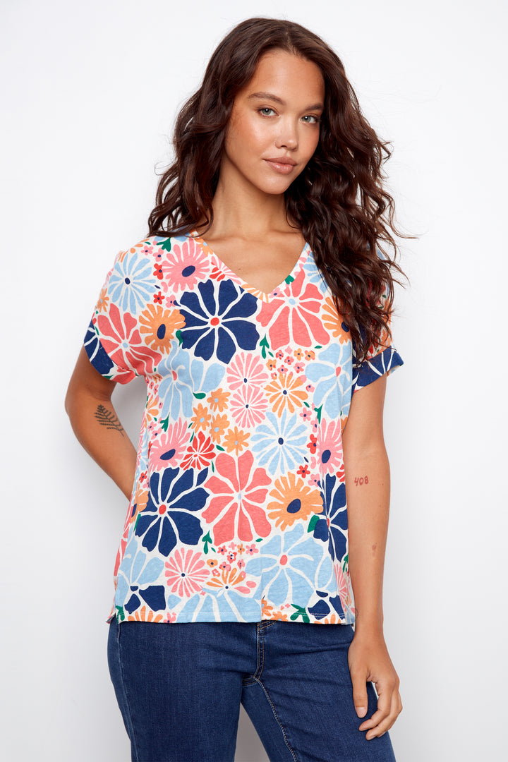 Woman wearing a colorful floral top against a white background