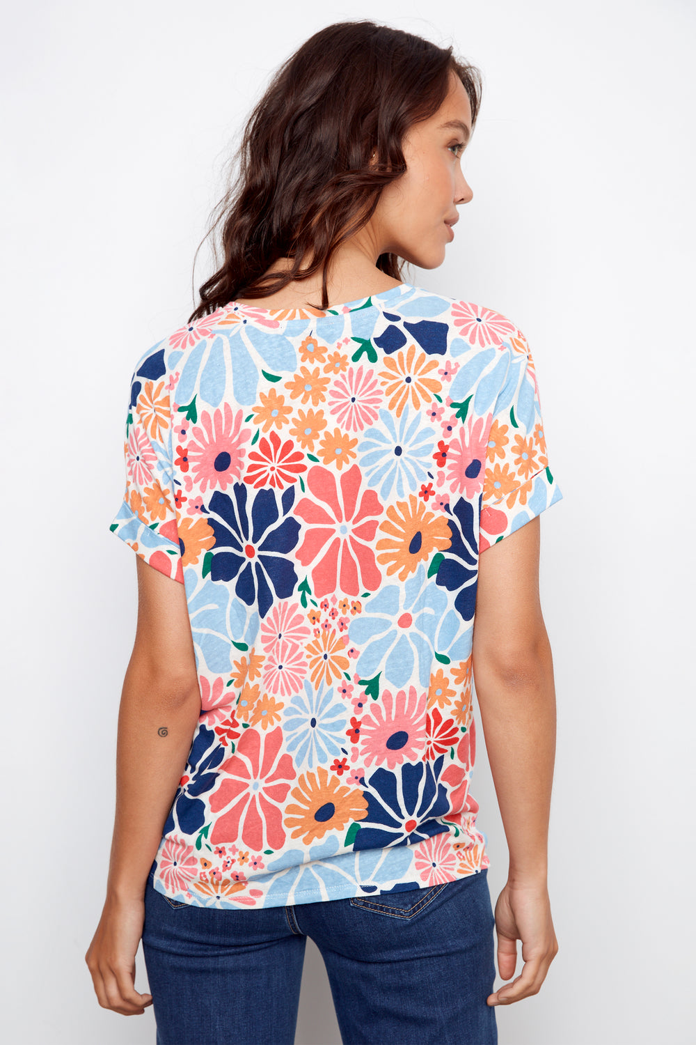 Woman wearing a colorful floral-patterned shirt against a white background